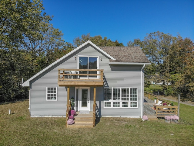 rear view of house featuring a yard, roof with shingles, and a balcony