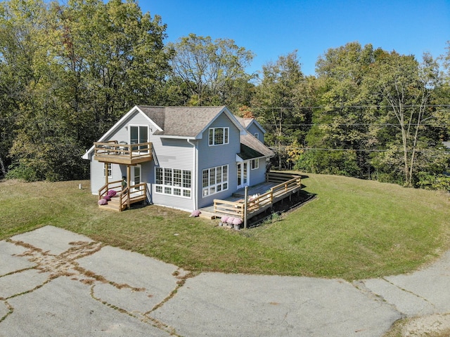 view of front of house featuring a shingled roof, a deck, and a front lawn