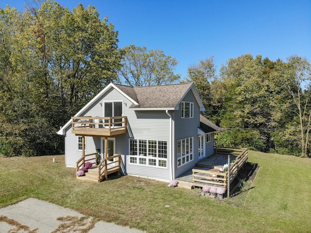 back of property with a wooden deck, a shingled roof, and a yard