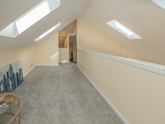 bonus room with carpet floors, vaulted ceiling with skylight, and baseboards