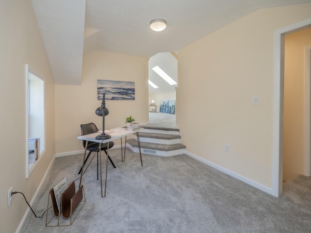 interior space with lofted ceiling with skylight, carpet flooring, and baseboards