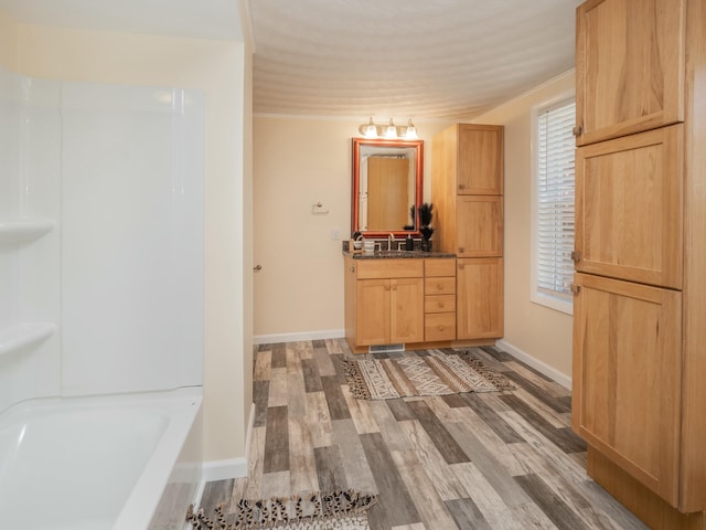 bathroom featuring a bathing tub, wood finished floors, vanity, and baseboards