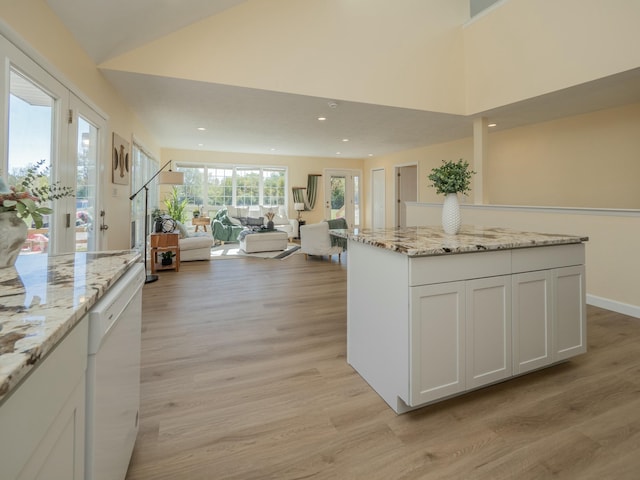 kitchen with light stone counters, light wood finished floors, recessed lighting, open floor plan, and white dishwasher