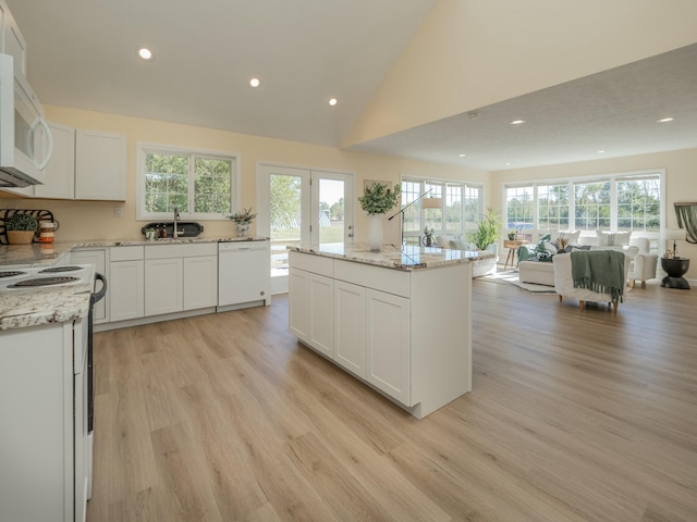 kitchen featuring white appliances, plenty of natural light, light wood finished floors, and open floor plan