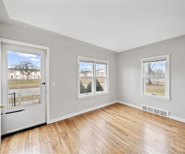 interior space featuring a wealth of natural light, wood-type flooring, visible vents, and baseboards