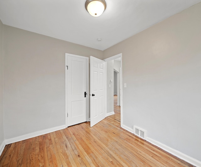 unfurnished bedroom featuring light wood-style flooring, a closet, visible vents, and baseboards