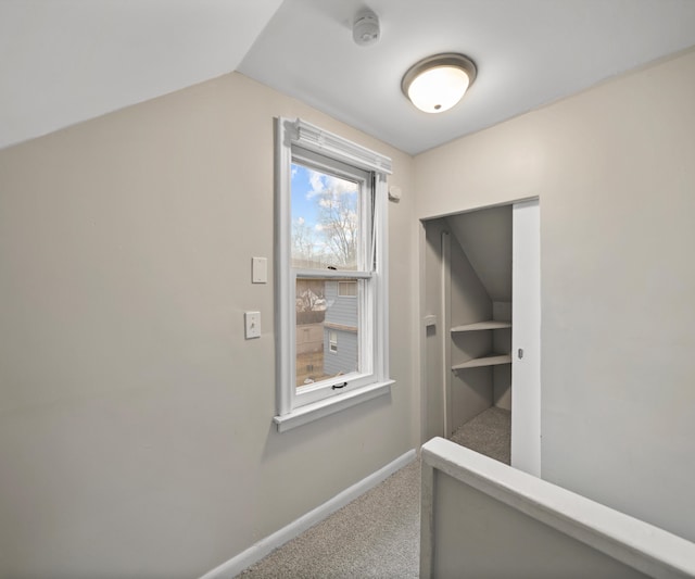 corridor with lofted ceiling, carpet floors, and baseboards