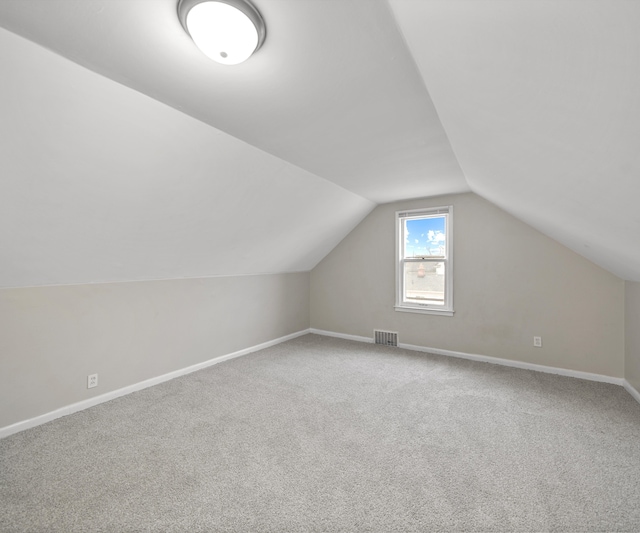 additional living space featuring lofted ceiling, carpet flooring, visible vents, and baseboards