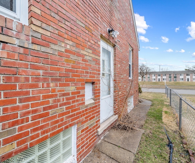 view of side of property featuring brick siding and fence