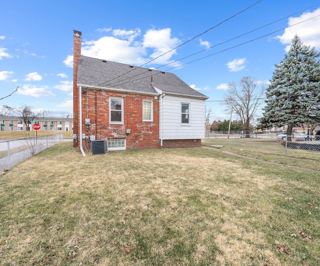 exterior space with a chimney, a shingled roof, a lawn, central AC unit, and a fenced backyard