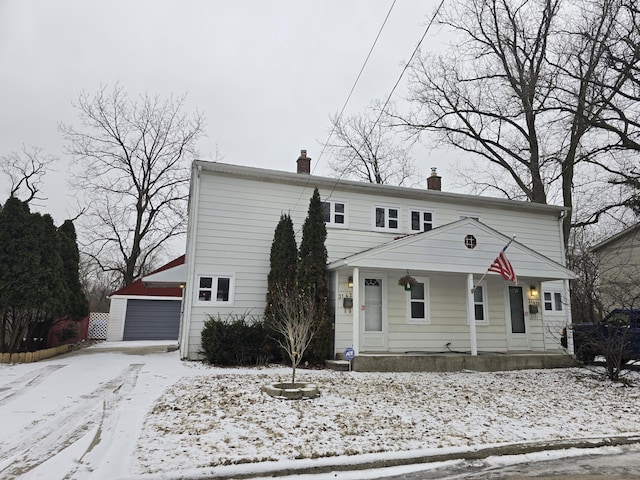 view of front of home with an outbuilding, a porch, a chimney, and a detached garage