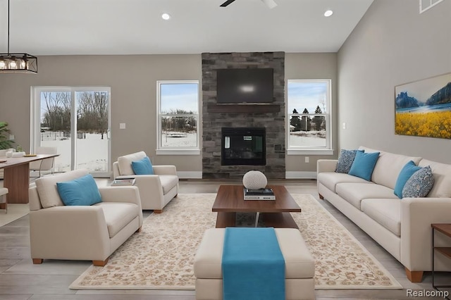 living room with recessed lighting, a large fireplace, baseboards, and ceiling fan with notable chandelier