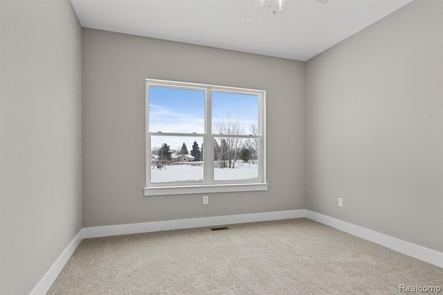 carpeted spare room with baseboards, visible vents, and a ceiling fan