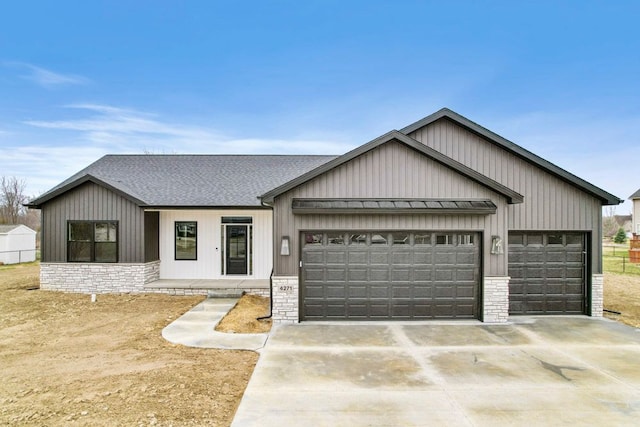 modern farmhouse style home with a garage, driveway, a standing seam roof, a shingled roof, and stone siding
