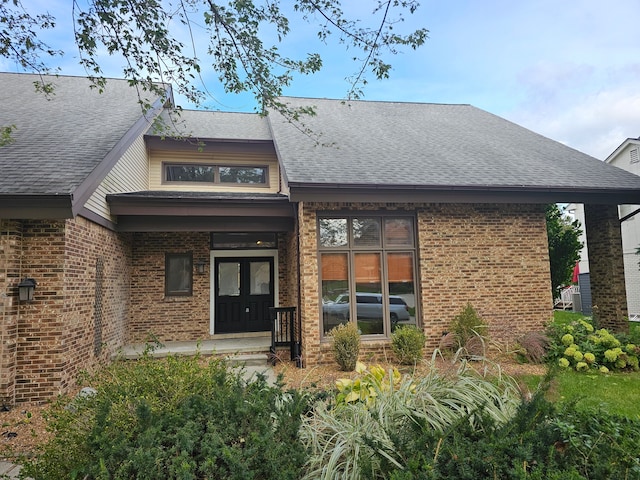 back of property featuring french doors, brick siding, and a shingled roof