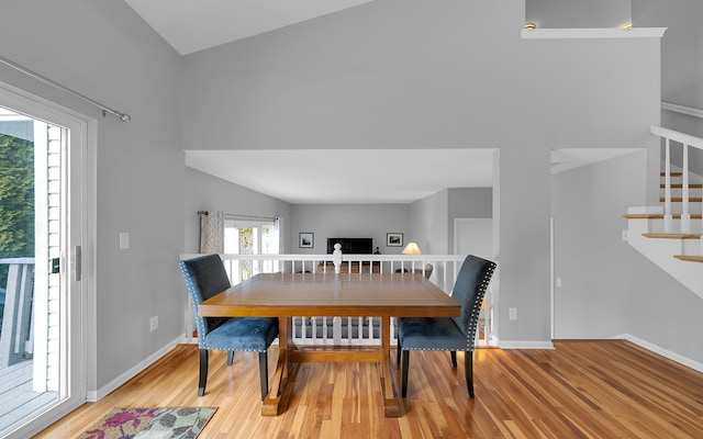 dining room with stairs, light wood-type flooring, and baseboards