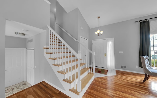 foyer entrance featuring a chandelier, visible vents, baseboards, and wood finished floors