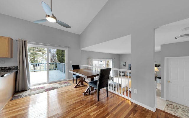 dining space with a healthy amount of sunlight, high vaulted ceiling, light wood-type flooring, and a ceiling fan