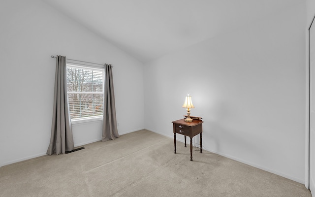 carpeted empty room with baseboards and vaulted ceiling