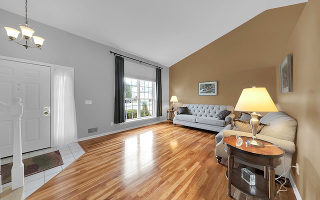 living room featuring baseboards, visible vents, vaulted ceiling, a notable chandelier, and light wood-type flooring