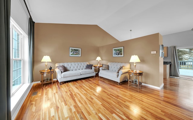 living room featuring visible vents, lofted ceiling, light wood-style floors, and baseboards