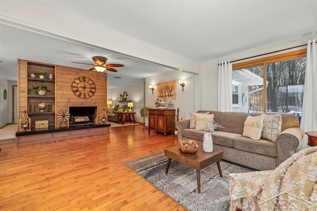 living room with a ceiling fan, a fireplace, and wood finished floors