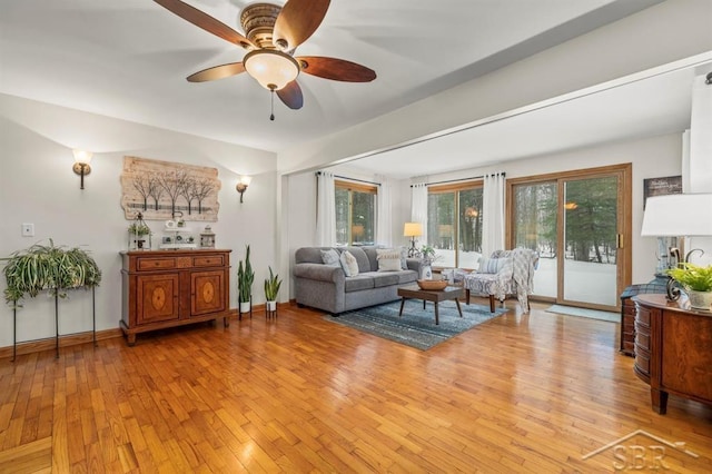 living room featuring a ceiling fan, light wood-type flooring, and baseboards