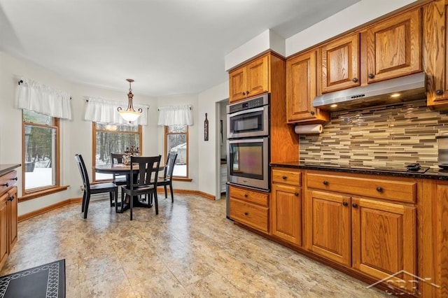 kitchen featuring black electric stovetop, stainless steel double oven, under cabinet range hood, backsplash, and brown cabinetry