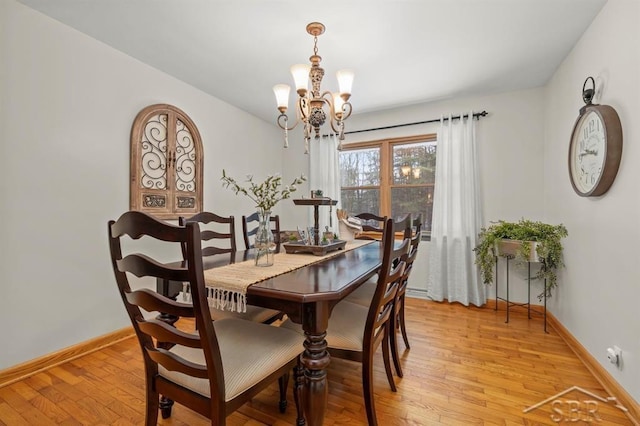 dining room with a chandelier, light wood-style flooring, and baseboards