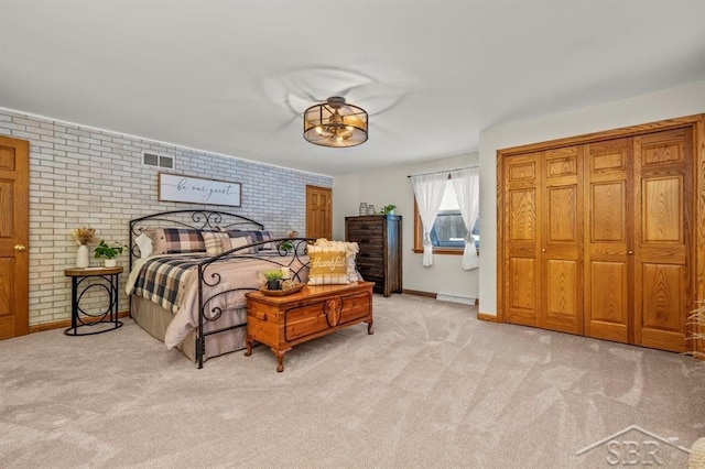 bedroom with brick wall, a baseboard radiator, visible vents, and light colored carpet