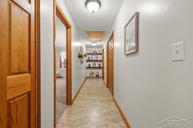 corridor with attic access and baseboards