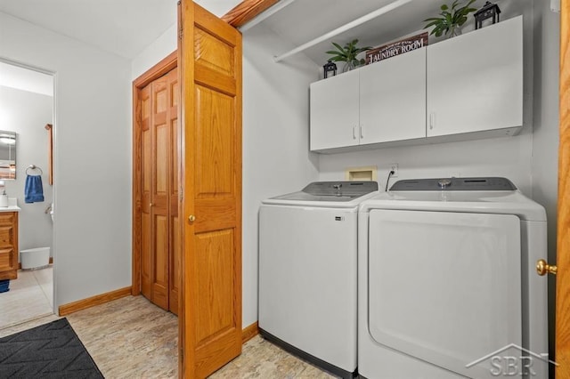 laundry room featuring washing machine and dryer, cabinet space, and baseboards