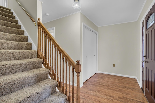 entrance foyer with baseboards, stairway, wood finished floors, and crown molding