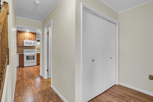 corridor with light wood-style floors, baseboards, and ornamental molding