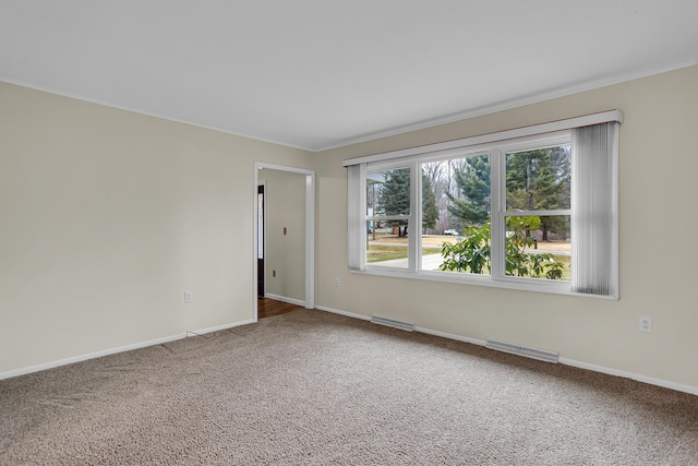 carpeted spare room featuring crown molding, visible vents, and baseboards