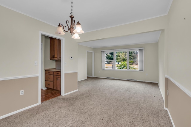 empty room featuring visible vents, ornamental molding, carpet flooring, a chandelier, and baseboards