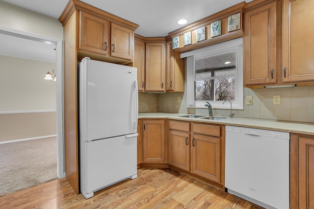 kitchen featuring tasteful backsplash, light countertops, brown cabinetry, a sink, and white appliances