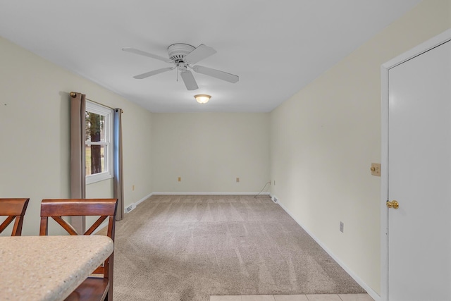 empty room featuring baseboards, ceiling fan, and light colored carpet