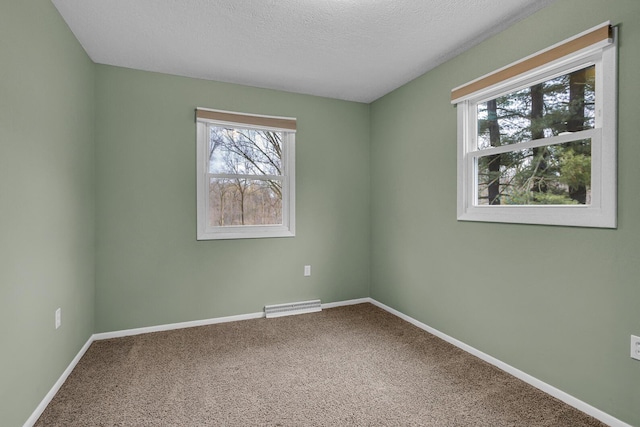 carpeted spare room featuring baseboards, visible vents, and a textured ceiling