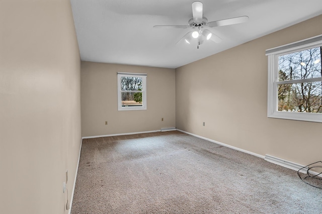 carpeted spare room featuring plenty of natural light, visible vents, baseboards, and a ceiling fan