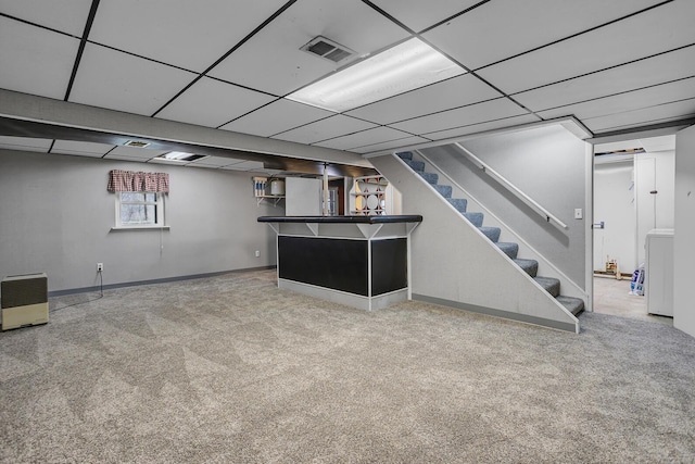 below grade area featuring a drop ceiling, baseboards, stairway, a bar, and carpet