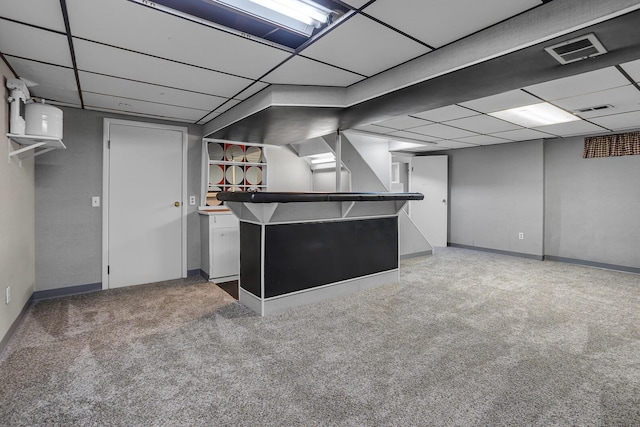 finished basement featuring a paneled ceiling, visible vents, and carpet flooring