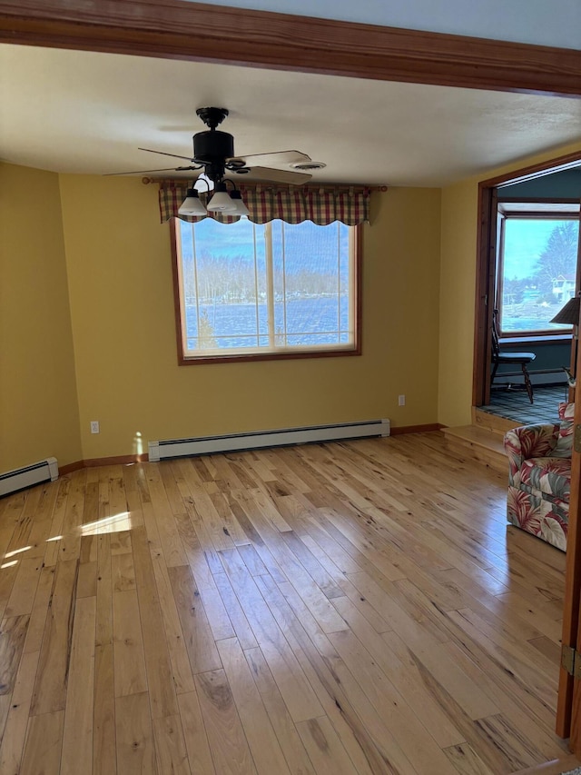 spare room featuring a ceiling fan, light wood-type flooring, baseboards, and baseboard heating