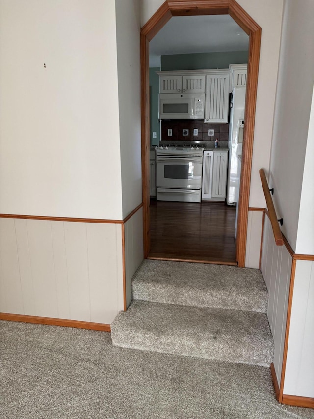 stairway featuring wainscoting and carpet