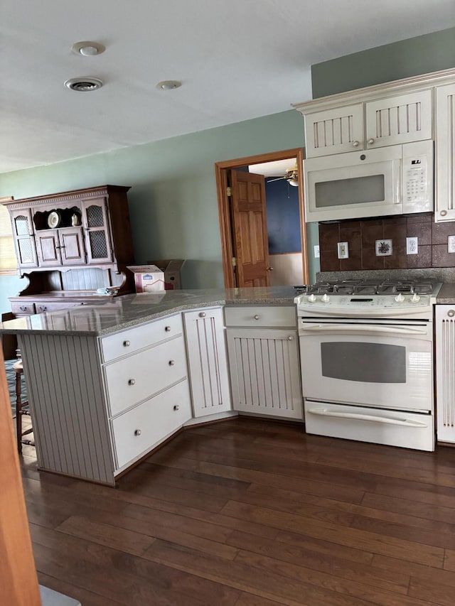 kitchen featuring white appliances, backsplash, and dark wood-type flooring