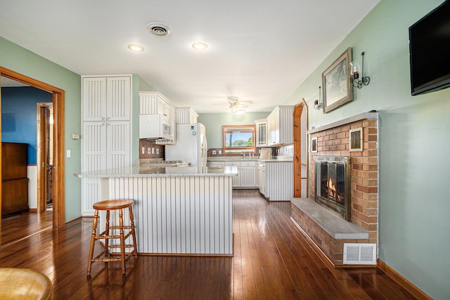 222 Crockett Dr, Quincy, MI 49082 - kitchen with a ceiling fan, a kitchen bar, white cabinetry, dark wood-style flooring, and recessed lighting