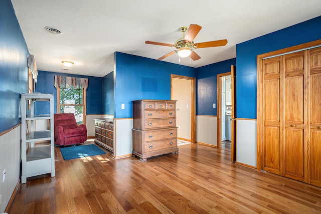 222 Crockett Dr, Quincy, MI 49082 - bedroom featuring a wainscoted wall, wood finished floors, a closet, and a ceiling fan
