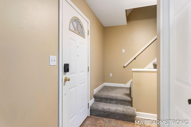 carpeted entryway featuring stairs and baseboards