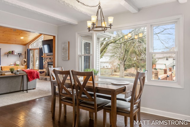 dining room featuring beam ceiling, a fireplace, dark wood finished floors, a notable chandelier, and baseboards