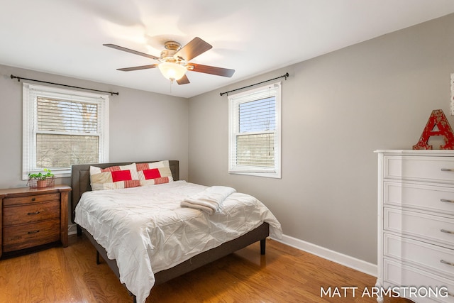 bedroom with ceiling fan, multiple windows, light wood-style flooring, and baseboards